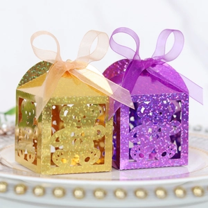 Detail of laser-cut bear design on glitter gold and purple party favor candy boxes