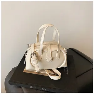 Detail of a creamy beige Boston bag featuring a unique leather heart-shaped decoration