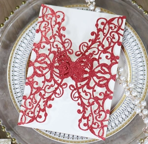 Macro shot of laser-cut red glitter butterfly invitation with floral patterns