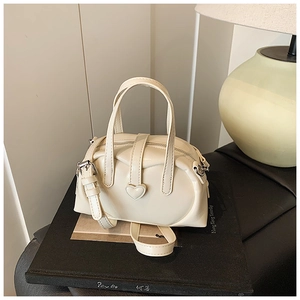 Macro shot of cream white mini bowling bag with heart buckle on art book stand