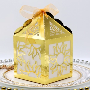 Detailed view of golden laser-cut house-shaped gift box with orange organza ribbon bow