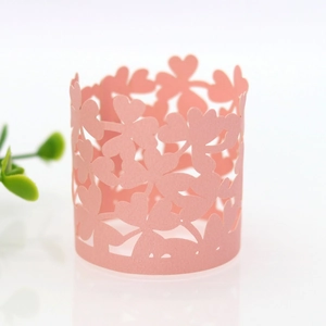 Macro detail of laser-cut pink paper cupcake wrapper with intricate clover hollow pattern