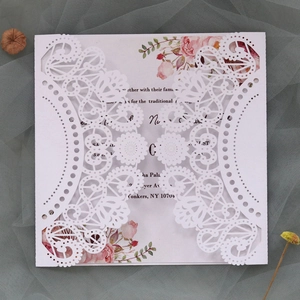 Detailed macro view of laser-cut lace wedding invitation with floral printed inner card