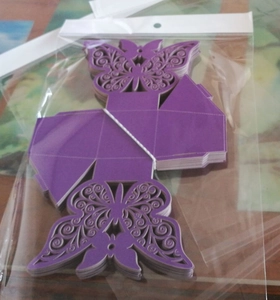 Detailed laser-cut purple butterfly favor boxes flat-packed in clear plastic packaging