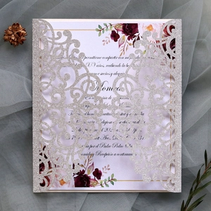 Detail of silver glitter laser-cut wedding invitation with elegant floral inner card