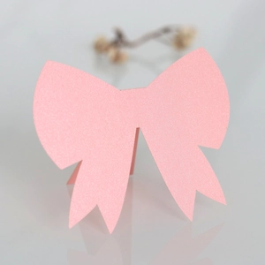 Macro shot of pink glitter bow card with detailed texture for wedding guest table setting