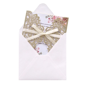 Close-up of laser cut glitter wedding invitation set with floral insert and cream ribbon
