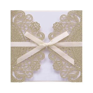 Detailed close-up of champagne gold glitter laser-cut lace invitation with a cream satin bow