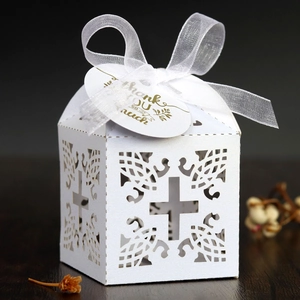 Detail of white laser-cut wedding favor box with cross design and thank you tag