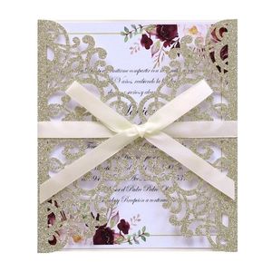 Laser cut gold glitter wedding invitation with floral insert and cream satin ribbon bow