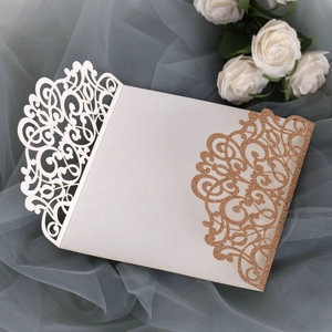Detail of laser-cut wedding invitation with cream paper and gold glitter floral patterns