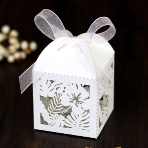 Detail of laser-cut hibiscus and palm leaf patterns on white wedding favor gift box