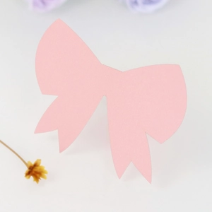 Detail of pink laser-cut 3D bow place card for weddings showing fine paper texture