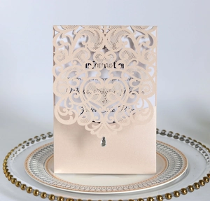 Detail of champagne gold laser cut wedding invitation with lace pattern and rhinestone