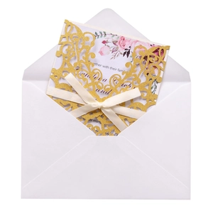Detail of laser cut gold glitter invitation cover with elegant silk ribbon and floral insert