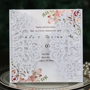 Détail d'invitation de mariage blanche découpée au laser avec insert floral sur plateau