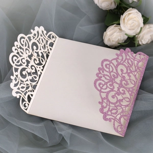 Detail of laser-cut scroll patterns on cream paper with pink glitter finish for invitations