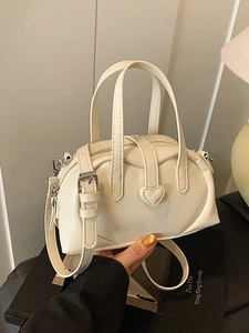 Chic cream leather heart buckle crossbody bag shown with top handles and shoulder strap