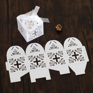 Macro view of white laser-cut wedding favor box featuring cross design and thank you tag