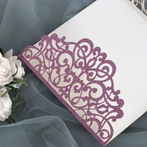 Macro detail of laser-cut European floral patterns on purple glitter wedding invitation