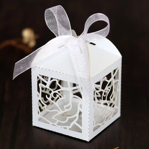 Detail of laser-cut rose pattern on white wedding favor box with a sheer organza ribbon