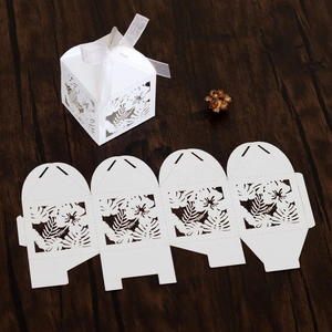Macro view of white laser-cut floral wedding favor box with a delicate chiffon ribbon