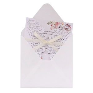 Detail of laser-cut lace wedding invitation set with floral card, envelope and cream ribbon
