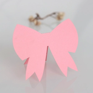 Detailed view of pink bow-shaped paper place cards for wedding table seating and decor