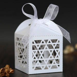 Detail of laser-cut white favor box with Star of David patterns and organza ribbon bow