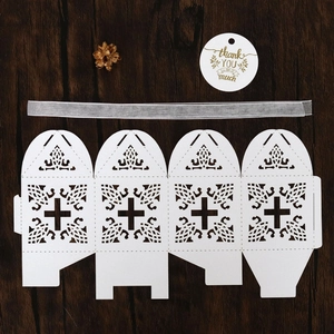 Flat lay of laser-cut white cross candy box with ribbon and gold foil thank you tag