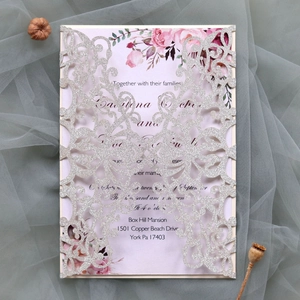 Detail of silver laser-cut wedding invitation with glitter finish and floral inner card