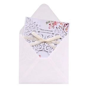 Détail d'invitation de mariage blanche découpée au laser avec ruban et motifs floraux