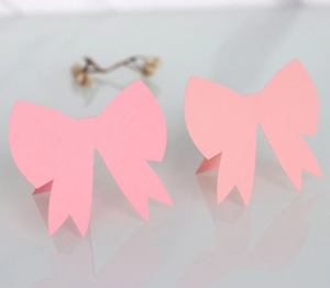 Detail of pink paper laser-cut 3D bow place cards for weddings on a white surface