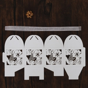 Laser-cut white gift box with tropical leaf patterns and matching white ribbon detail