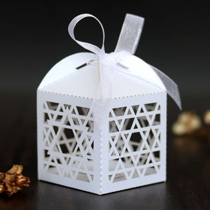 Close-up of white hollow star candy box with organza ribbon on dark wood surface