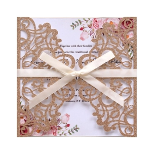 Detail of laser-cut glitter gold wedding invitation with satin bow and floral inner card