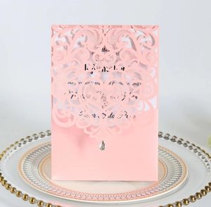 Detailed laser-cut pink invitation card with heart patterns and rhinestone on a ceramic plate