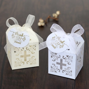 Detail of laser-cut cross pattern on ivory wedding favor box with organza ribbon