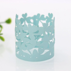 Macro detail of laser-cut light blue paper napkin ring with clover and heart patterns