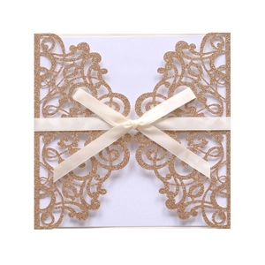 Detail of laser cut champagne gold glitter invitation cover with elegant silk ribbon bow