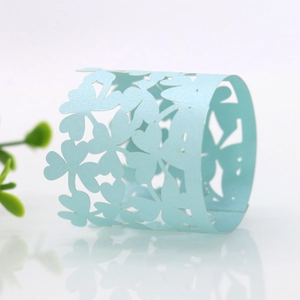 Detailed view of light blue pearlescent paper napkin rings with hollow clover patterns