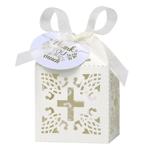 White laser-cut wedding favor box with cross design, ribbon bow, and thank you tag