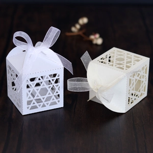 Close-up of laser-cut hexagonal star favor boxes with elegant organza ribbons