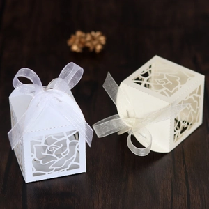 Detail of laser-cut rose hollow favor box with elegant organza ribbon on wood