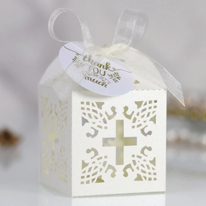 Detail view of laser-cut white cross favor box with ribbon and Thank You tag