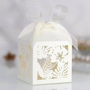 Detail of laser-cut hibiscus flower and leaf patterns on white paper wedding favor box