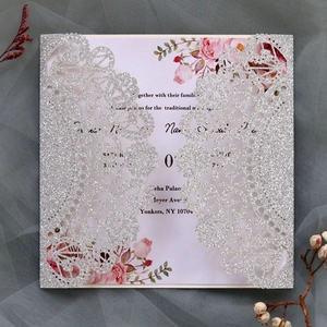 Close-up of silver glitter laser-cut lace wedding invitation with pink rose floral card