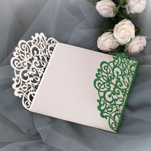 Close-up of laser cut floral patterns with green glitter coating on wedding invitation