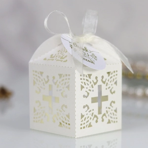 Detail of white laser-cut wedding favor box with cross pattern and thank you tag