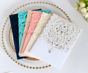 Close-up of laser-cut floral wedding invitations in multiple colors on a porcelain plate
